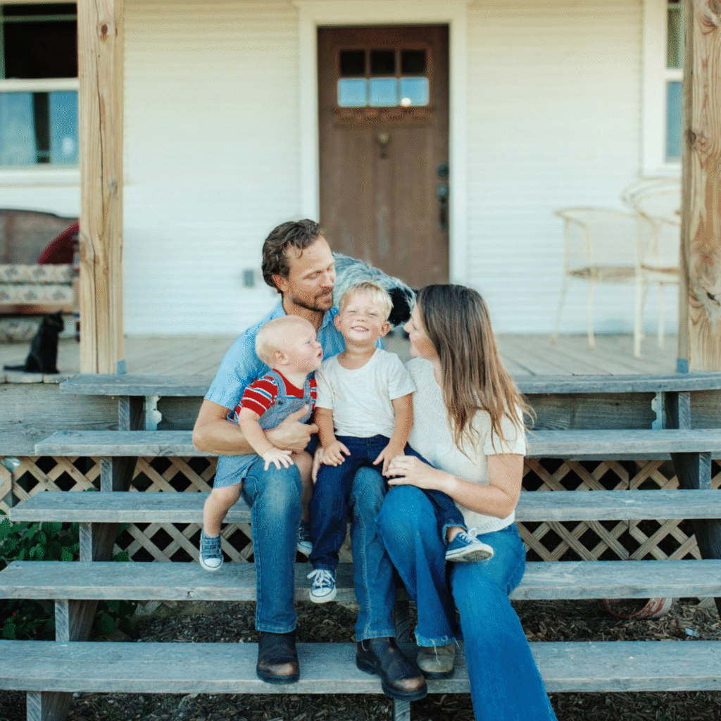 husband, wife, and two little boys on farmhouse porch at Respite Bee Farm