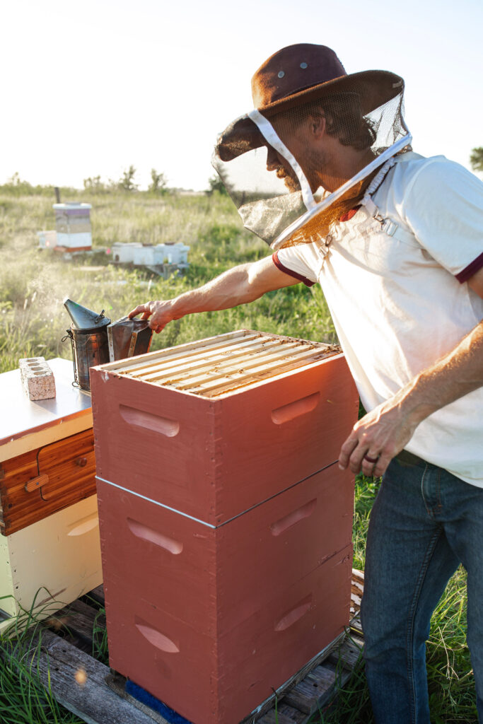 Ben Baecker working on bees hives in Texas in front of a beekeeping class
